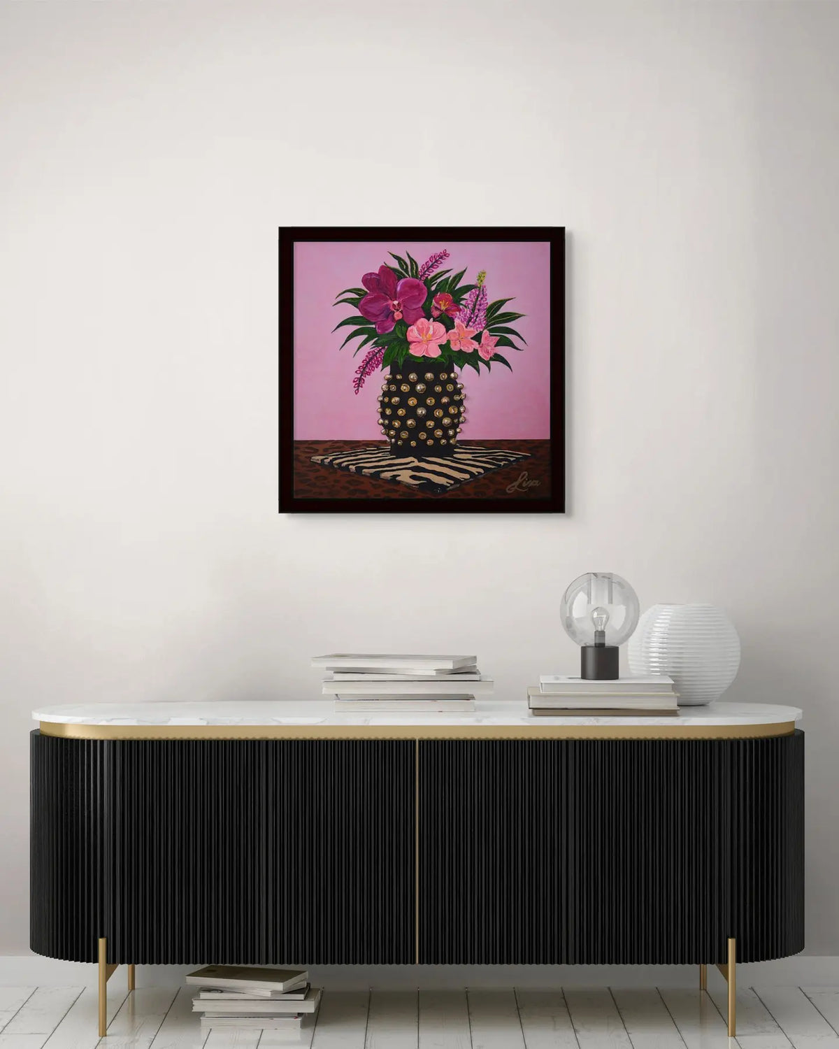 Original floral painting in a black frame displayed above a black console table.